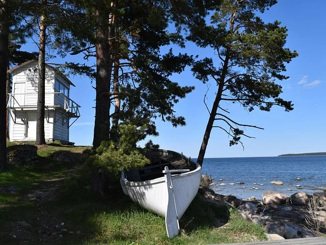 Un bateau en bois blanc reposant sur le rivage près d'un petit bâtiment blanc.