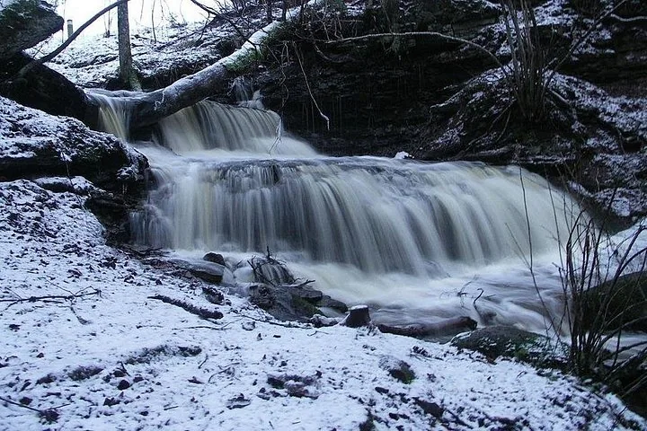 Petite cascade dévalant les rochers dans un décor hivernal enneigé.